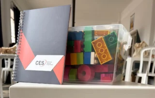 Cuaderno del CES junto a bloques de construcción utilizados en la actividad sobre desarrollo y testing de software.